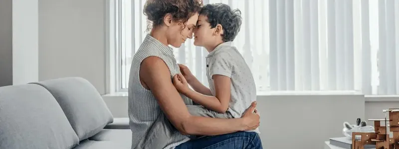 Woman touching foreheads with the child sitting in her lap